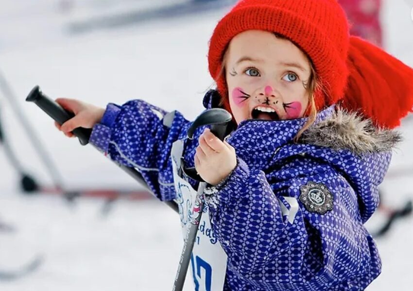 Barn som har ansiktsmaling som en mus og går på ski. Foto